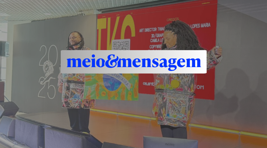 Dois palestrantes no palco exibem painel colorido com logotipo meio&mensagem sobreposto diante de um banner vermelho